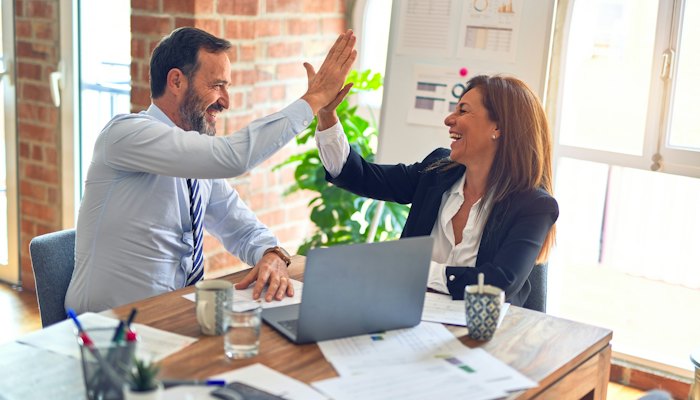 Empresário e consultora comemorando o resultado com um toca aqui