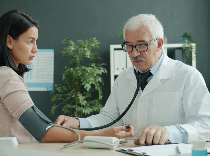 Médico do trabalho medindo a pressão de uma funcionária